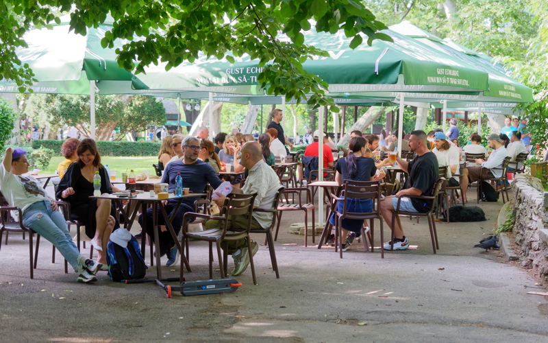 17 - A lively outdoor beer garden with large green umbrellas providing shade over shared tables